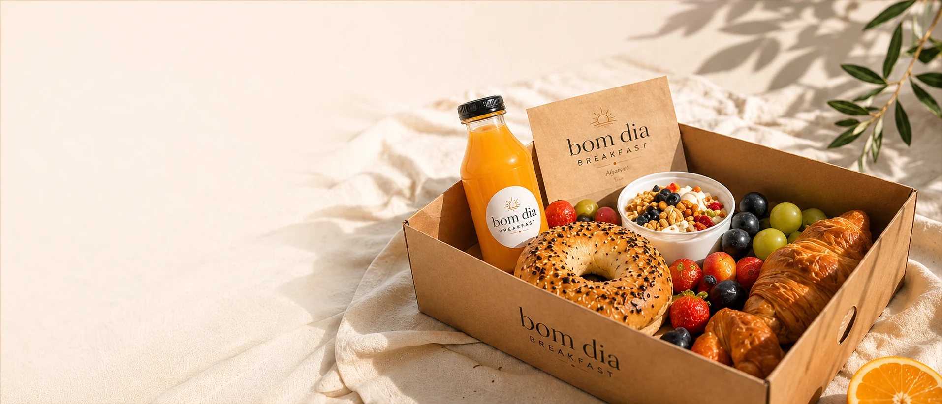 A Bom Dia breakfast box with bagel, fruit, yogurt and fresh orange juice